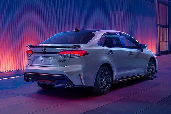 View of behind Toyota Corolla on sidewalk with led lights in background